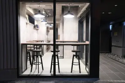 a bar with stools is seen through a window at N Plus Hotel Akihabara in Tokyo