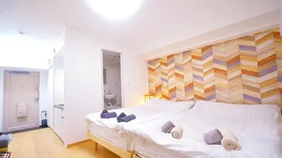 a bedroom with a white bed with a striped wall at TOKYO ICHIBAN SHINJUKU in Tokyo