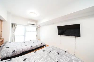 a bedroom with two beds and a flat screen tv at TOKYO ICHIBAN SHINJUKU in Tokyo