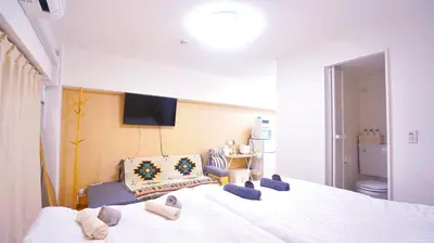 a bedroom with a large white bed with blue chairs at TOKYO ICHIBAN SHINJUKU in Tokyo
