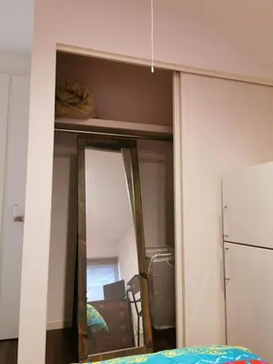a mirror in a bedroom with a bed and a refrigerator at Bell house in Tokyo