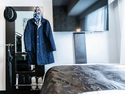 a robe hanging on a wall next to a bed at APA Hotel Asakusa Kuramae Kita in Tokyo