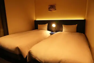 two beds in a small room with two lamps at Nplus HOTEL Higashikanda-akihabara in Tokyo
