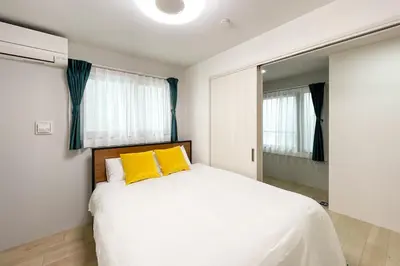 a bedroom with a large white bed with yellow pillows at \u30bf\u30b9\u30adsmart\u66d9\u6a4b in Tokyo