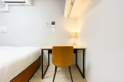 a desk with a chair next to a bed at \u30bf\u30b9\u30adsmart\u66d9\u6a4b in Tokyo