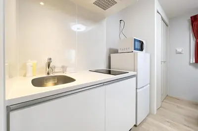 a white kitchen with a sink and a refrigerator at \u30bf\u30b9\u30adsmart\u66d9\u6a4b in Tokyo