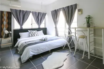 a bedroom with a bed and a table and windows at NEW Heart of Shibuya Prime Studio, Kamiyama Inn! in Tokyo