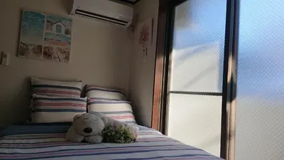 a teddy bear sitting on a bed next to a window at JING HOUSE渋谷ダブルベッド/新宿・渋谷駅近 in Tokyo