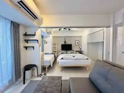 a bedroom with a bed and a couch and a tv at FLOWER TERRACE Higashi Shinjuku in Tokyo
