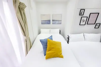 two beds in a small bedroom with yellow and blue pillows at LUANAHOTEL IN YOTSUYA in Tokyo