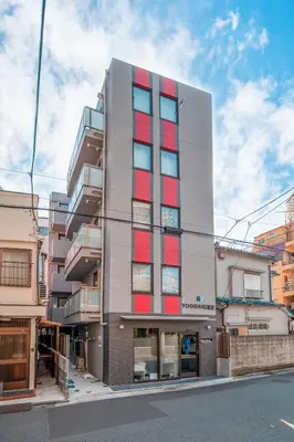 a tall building with red windows on a street at Ustay Nippori in Tokyo