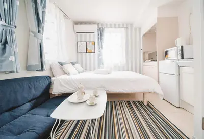 a bedroom with a bed and a couch and a table at Ustay Nippori in Tokyo
