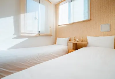 two beds in a room with two windows at Ustay Nippori in Tokyo