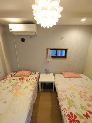 a room with two beds and a table and a chandelier at kaneshiro guest house in Tokyo
