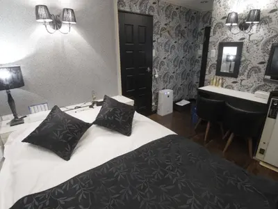 a bedroom with a bed with black pillows and a sink at SKYROAD Adult Only in Tokyo