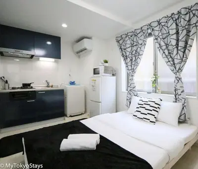 a bedroom with a large white bed and a kitchen at Skytree & Asakusa Easy Access Bell Flat Inn #2 in Tokyo