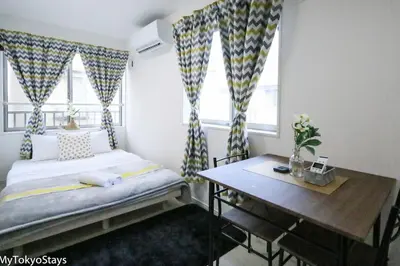 a bedroom with a bed and a table and windows at Skytree Easy Access Studio Apt Bell Flat Inn #3 in Tokyo