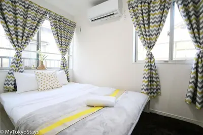 a bedroom with a bed and windows with curtains at Skytree Easy Access Studio Apt Bell Flat Inn #3 in Tokyo