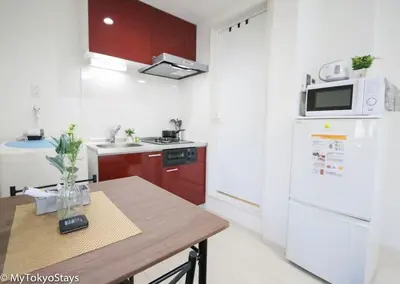 a kitchen with a table and a white refrigerator at Skytree Easy Access Studio Apt Bell Flat Inn #3 in Tokyo