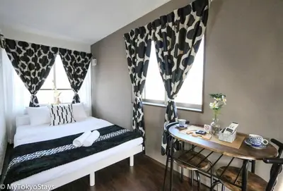 a bedroom with a bed and a table and two windows at Easy Access to Skytree 1BR Bell Flat Inn #5 in Tokyo