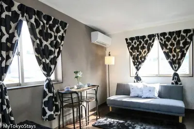 a living room with a couch and a table and windows at Easy Access to Skytree 1BR Bell Flat Inn #5 in Tokyo