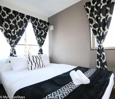 a bedroom with a bed with black and white curtains at Easy Access to Skytree 1BR Bell Flat Inn #5 in Tokyo