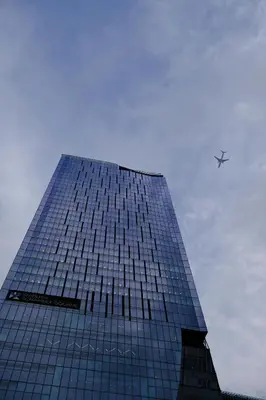 a tall glass building with an airplane in the sky at NEW! Time Square Shibuya Modern Unit. Prime Location in Tokyo
