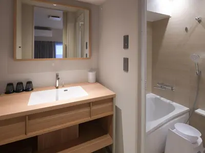 a bathroom with a sink and a mirror and a tub at Vessel Inn Asakusa Tsukuba Express in Tokyo