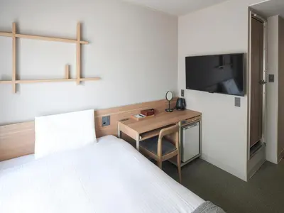 a bedroom with a bed and a desk and a tv at Vessel Inn Asakusa Tsukuba Express in Tokyo