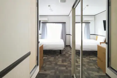 a room with two beds and a mirror at Vessel Inn Asakusa Tsukuba Express in Tokyo