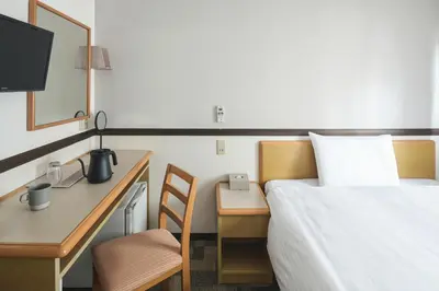 a hotel room with a bed and a desk and a bed at Vessel Inn Asakusa Tsukuba Express in Tokyo