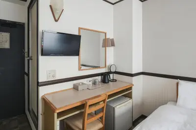 a hotel room with a desk with a mirror and a bed at Vessel Inn Asakusa Tsukuba Express in Tokyo