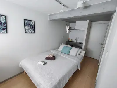 a small bedroom with a bed and a kitchen at SaffronCasa Asakusabashi by Tranova in Tokyo