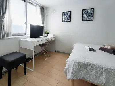 a bedroom with a bed and a desk with a computer at SaffronCasa Asakusabashi by Tranova in Tokyo