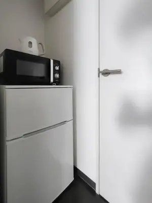 a microwave sitting on top of a refrigerator at SaffronCasa Asakusabashi by Tranova in Tokyo