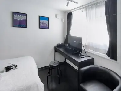 a bedroom with a desk and a bed with a computer at SaffronCasa Asakusabashi by Tranova in Tokyo