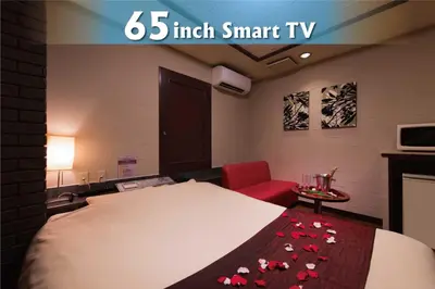 a room with a large bed with a red chair and a red blanket with roses at Hotel Will\u6c60\u888b Adult Only in Tokyo