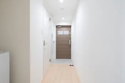 a hallway with white walls and a wooden door at MAT OSHIAGE Ⅱ in Tokyo