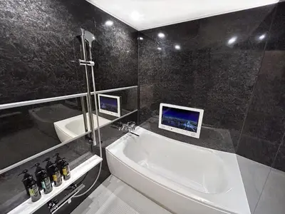 a bathroom with a sink and a bath tub with two monitors at Hotel QUEEN ANNEX in Tokyo