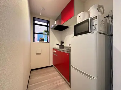 a kitchen with a white refrigerator and red cabinets at nestay inn tokyo asakusa in Tokyo