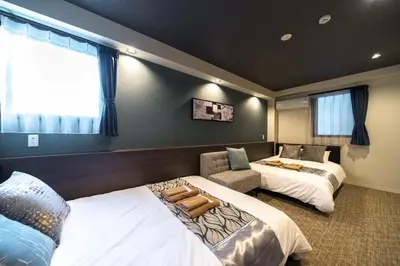 a hotel room with two beds and a chair at UCHI Asakusabashi in Tokyo