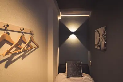 a bedroom with a bed and a light on the wall at UCHI Asakusabashi in Tokyo