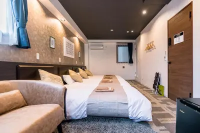 a large bed in a room with a couch at UCHI Asakusabashi in Tokyo