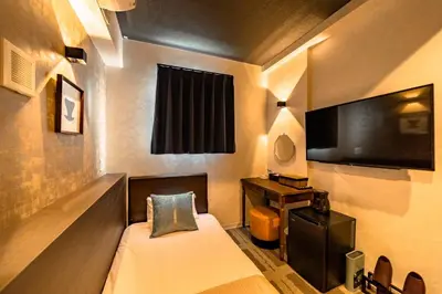 a hotel room with a bed and a flat screen tv at UCHI Asakusabashi in Tokyo