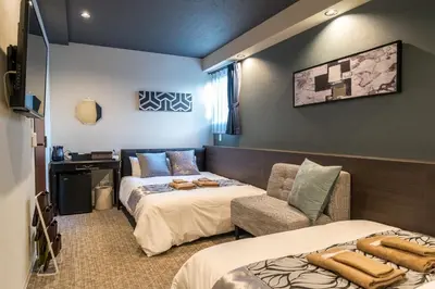 a hotel room with two beds and a chair at UCHI Asakusabashi in Tokyo
