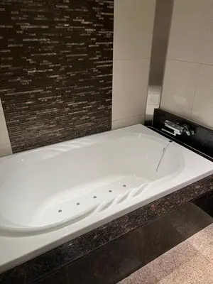 a white bath tub in a room with a brick wall at HOTEL Shuffle in Tokyo