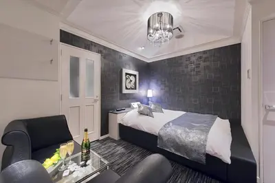 a bedroom with a bed and a chair and a table at HOTEL REFRAIN in Tokyo
