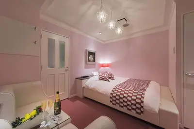 a pink bedroom with a bed and a table at HOTEL REFRAIN in Tokyo