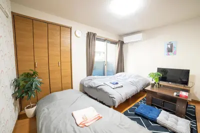 a bedroom with two beds and a desk and a tv at Minimalism HOTEL TOKYO Katsushika in Tokyo