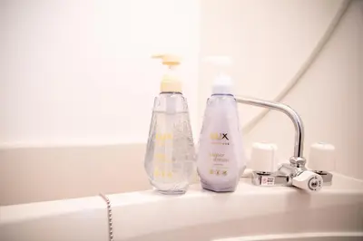 two bottles of detergent sitting on a bathroom sink at Minimalism HOTEL TOKYO Katsushika in Tokyo